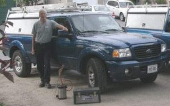 The original owner and operator of York Pest Control standing beside two blue trucks with white cabs